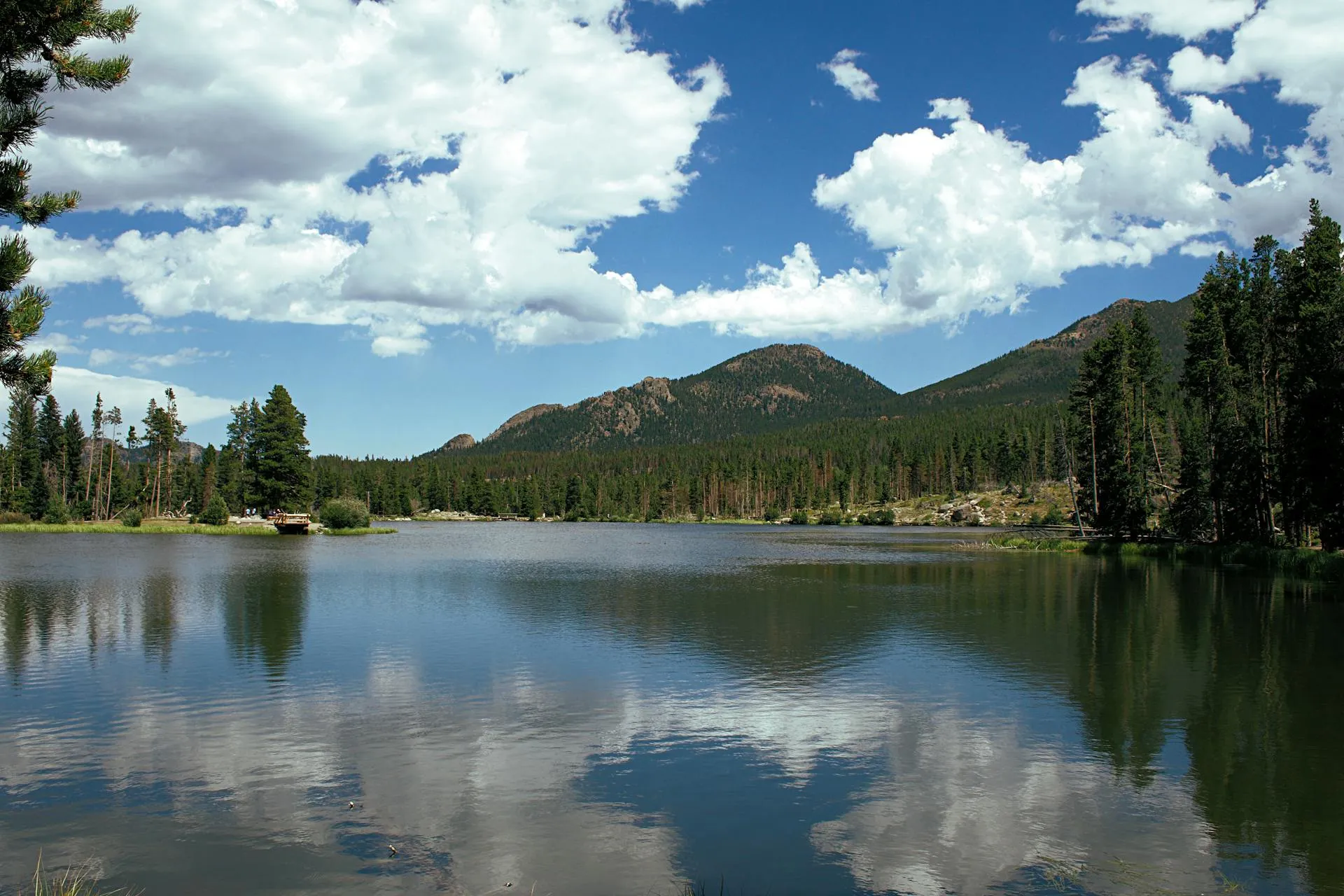 A serene lake reflecting a mountain in the background under a clear blue sky.